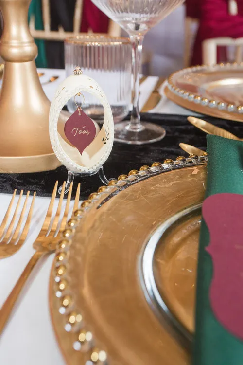 A table setup with gold plates and cutlery with a nameplate